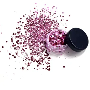 Detailed view of pink glitter powder in small jar with scattered festival makeup sequins.