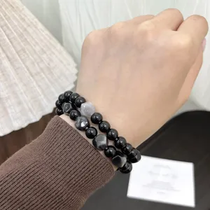 Detailed close-up of double-layer black and gray gradient cat eye bead bracelets worn on hand.