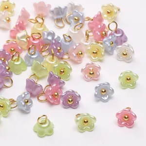 Closeup of colorful resin pearlescent mini flower pendants with gold loops for DIY jewelry making.