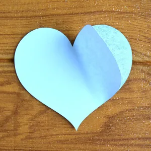 Vista di dettaglio di adesivo a cuore blu che mostra carta di supporto e strato adesivo.