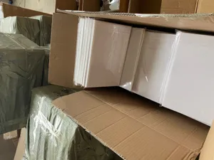 Factory detail view showing neatly stacked white acrylic mirror wall sticker panels inside boxes.
