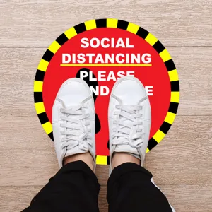 Detailed view of round social distancing floor sticker with warning design and clear text markings.