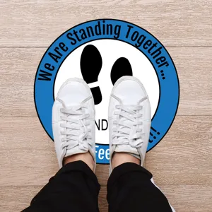 Detail view of social distancing floor sticker with footprint design on wooden floor.