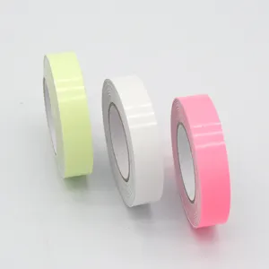 Detalle de primer plano de rollos de cinta adhesiva luminosa en amarillo, blanco y rosa.
