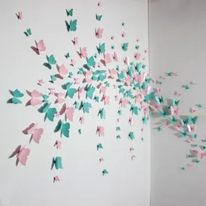 Detail shot of 3D pearlescent paper butterfly wall stickers in pink and teal for room decor.