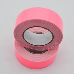 Primer plano detallado de rollos de cinta adhesiva fluorescente rosa brillante apilados.