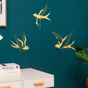 Close-up detail of golden mirror acrylic swallow wall stickers on a dark green wall, home decor.