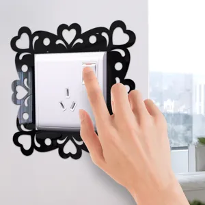 Close-up view of a black acrylic mirror switch sticker with heart pattern on a white wall.