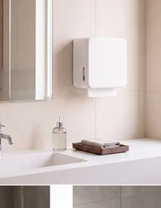Wall-mounted white paper towel dispenser detail view showcasing modern bathroom setup.