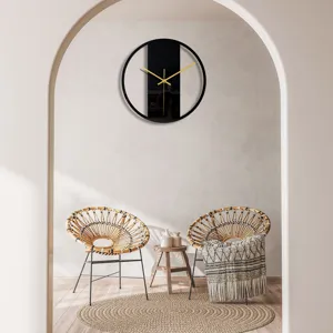 Detail de l'horloge murale moderne en acrylique noir, elegantes aiguilles dorees pour la deco.