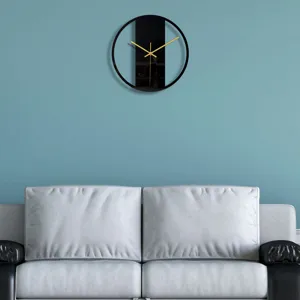 Horloge murale ronde noire minimaliste moderne avec des aiguilles dorées sur un mur.