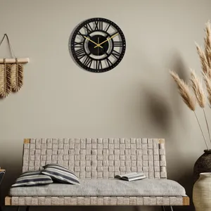Vue détaillée de l'horloge murale ronde en acrylique noir avec aiguilles dorées au salon.