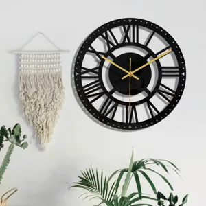 Détail horloge murale acrylique noire, chiffres romains et aiguilles dorées déco maison.