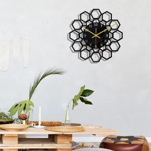 Moderne pendule murale en acrylique noir avec design alvéolé géométrique et aiguilles dorées.