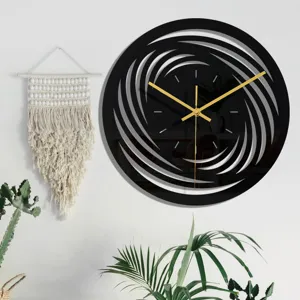 Gros plan d'horloge murale minimaliste en acrylique noir avec aiguilles dorées et motif tourbillon.