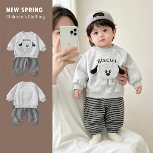 Infant boy wearing a grey puppy sweatshirt and striped pants in a detail showcase