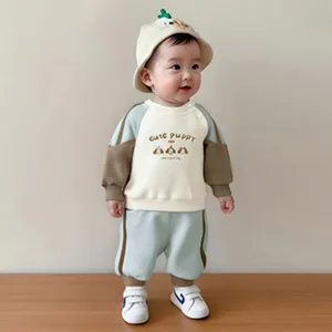 Cute infant baby boy wearing a pastel color block sweatshirt and pants outfit set