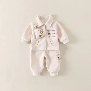 Close-up of baby boy cream outfit with cute cartoon dog patch and pocket details