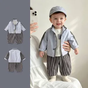 Detail of infant boy spring romper featuring light blue jacket and grey striped trousers
