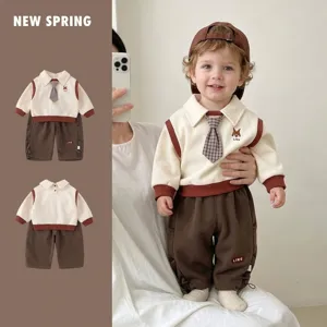 Detail shot of a stylish baby boy spring romper featuring a faux tie and brown pants