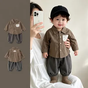 Vista dettagliata del set neonato con camicia marrone, decoro tasca e pantaloni grigi