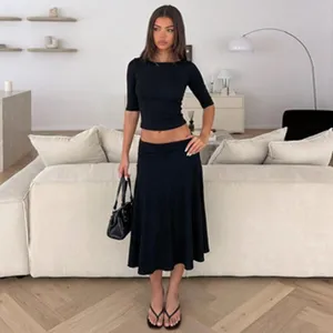 Modern two-piece black set with cropped medium-sleeve top and elegant midi skirt.