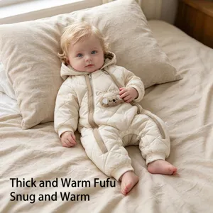 Close-up of a cute infant wearing a thick quilted winter hooded romper on a soft bed