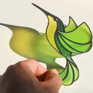 Close-up detail showing the translucent stained glass style hummingbird suncatcher casting shadow.