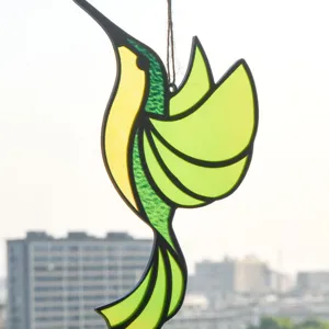 Close-up detail of the stained glass hummingbird suncatcher hanging by a window for decor.