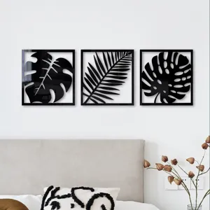 Detail shot of black acrylic mirror tropical leaf wall art in bedroom setting, modern decor.