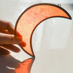 Primo piano dettagliato di un acchiappasole in vetro colorato a forma di luna crescente.