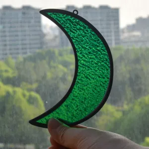 Acchiappasole luna crescente in vetro colorato verde con dettaglio di luce naturale.