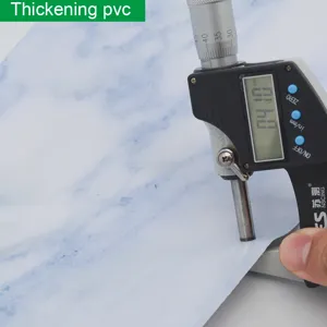Gros plan montrant la surface texturée et la mesure d'épaisseur de l'adhésif PVC marbre bleu.