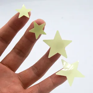 Detailed view of luminous star stickers displayed on fingers for size reference, glowing decor.