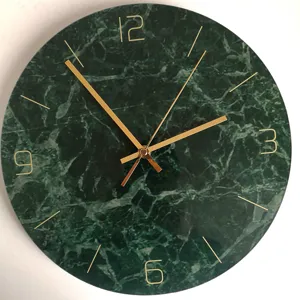 Close-up detail of dark green marble wall clock with elegant gold hands and minimalist markers.