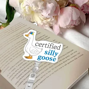Detailed shot of a cute duck badge reel holder with silly goose text on an open book background.