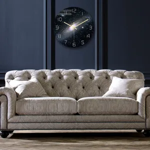 Vista de detalle de un reloj de pared con galaxia montado en pared oscura sobre sofá.