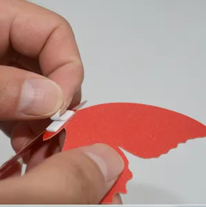 Close up detail showing adhesive foam tape application on red glitter butterfly wall sticker.