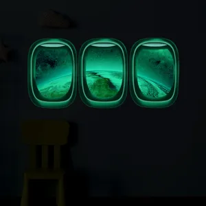 Sticker mural hublot d'avion phosphorescent avec motif espace et terre pour chambre d'enfant.