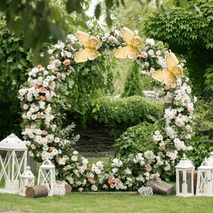 Detailed scene of large 3D pearlescent paper butterfly decorations on wedding floral arch setup.