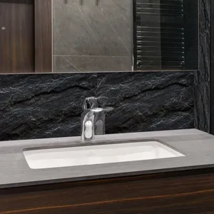 Lavabo encastrable céramique moderne avec robinet chrome et plan de toilette en pierre.