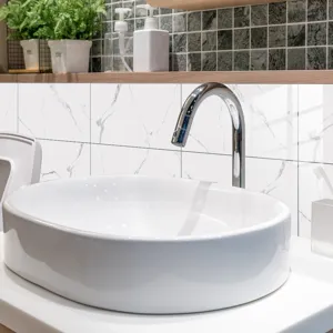Detail view of white marble tile stickers in a modern bathroom sink and faucet setting.
