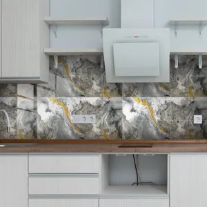Detailed view of grey and gold marble pattern tile stickers installed on modern kitchen wall.