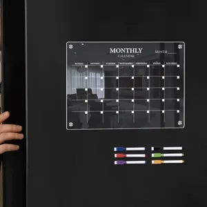 Transparent acrylic monthly calendar detail showing clear grid layout with colorful magnetic pens.