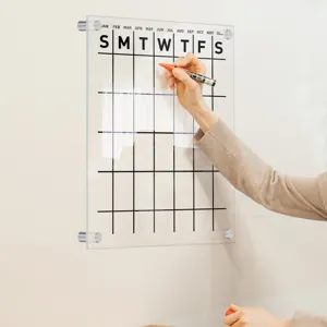 Clear acrylic wall-mounted calendar board detail view showing writable grid and monthly planner layout.