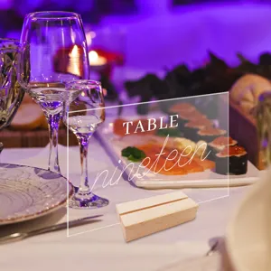 Clear acrylic table number sign with wood base, perfect for wedding table decor and party setups.