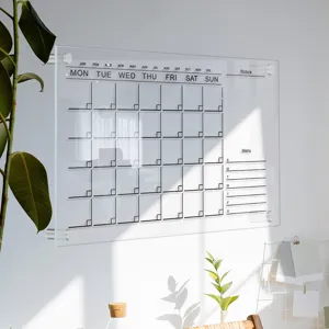 Clear acrylic monthly calendar wall planner board with metal standoffs and weekly notes layout.