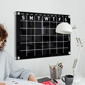 Detail view of black acrylic wall calendar planner with grid and month labels for office.