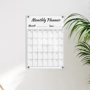 Wall-mounted transparent acrylic monthly planner detail scene, clear calendar grid and plant decor.