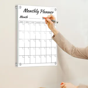 Clear acrylic monthly planner board detail view mounted on wall for daily office note taking.